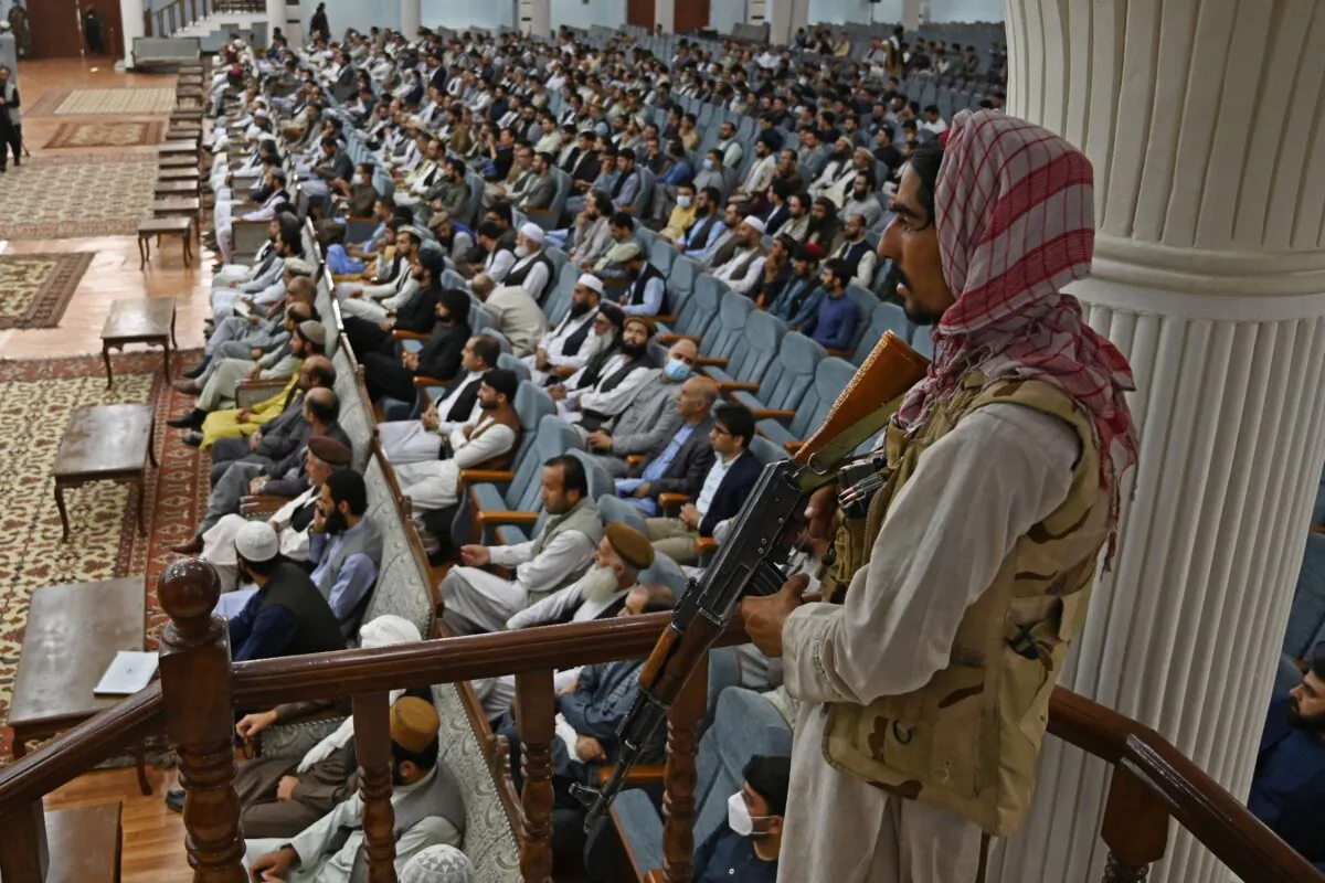 A Taliban fighter stands guard as the group's Higher Education Minister Abdul Baqi Haqqani speaks on the Taliban's higher education policies at the Loya Jirga Hall in Kabul on Aug. 29, 2021. Afghan women will be allowed to study at university but there will be a ban on mixed classes under Taliban rule, Haqqani said. (Aamir Qureshi/AFP via Getty Images)