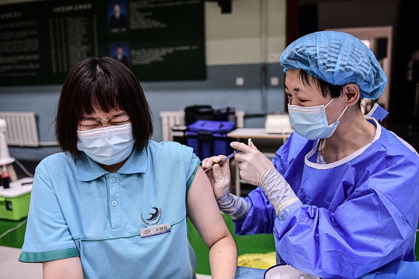 A student (L) reacts as she receives the Sinopharm COVID-19 vaccine at a high school in Shenyang in China's northeastern Liaoning Province on July 28, 2021. (STR/AFP via Getty Images)