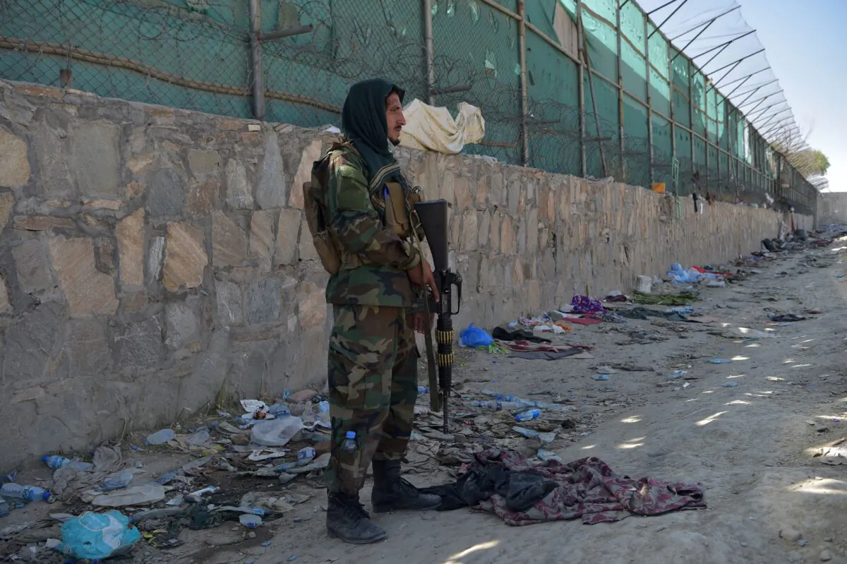 A Taliban fighter stands guard at the site of the Aug. 26 twin suicide bombs, which killed scores of people including 13 U.S. troops, at Kabul airport in Afghanistan on Aug. 27, 2021. (Wakil Kohsar/AFP via Getty Images)
