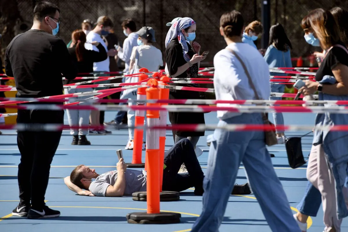 A man reads a book as he queues at a COVID-19 vaccination centre in Melbourne, Australia, on Sept. 1, 2021. (William West/AFP via Getty Images)