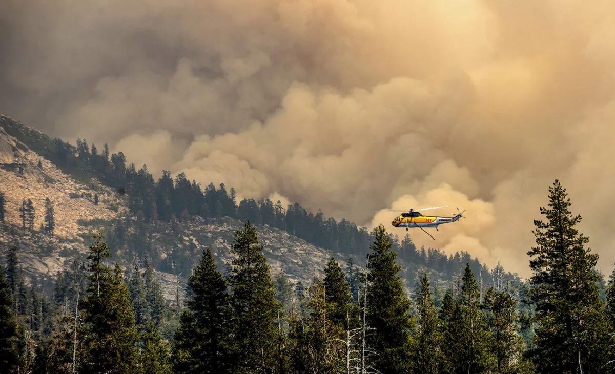 A helicopter flies over Wrights Lake while battling the Caldor Fire in Eldorado National Forest, Calif., on Sept. 1, 2021. (AP Photo/Noah Berger)