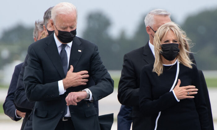 President Joe Biden, left, looks at his watch as he and First Lady Jill Biden attend the dignified transfer of the remains of fallen service members at Dover Air Force Base in Dover, Del., on Aug. 29, 2021. (Saul Loeb/AFP via Getty Images)