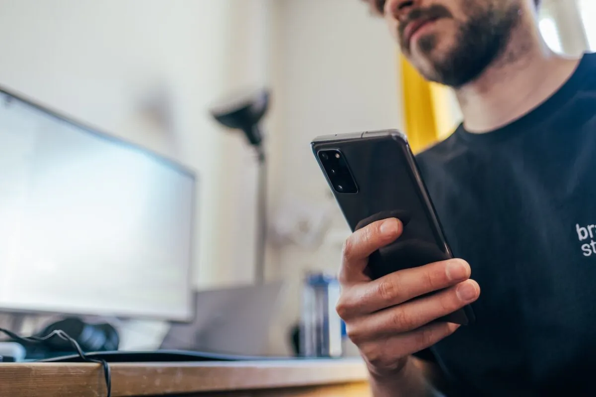 Man holding a phone while indoors. (Jonas Leupe/Unsplash)