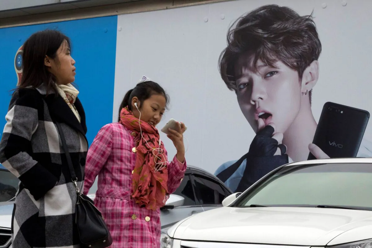 Chinese women walk past advertisement featuring teen idol Lu Han, also known as China's Justin Bieber in Beijing, China, on Oct. 21, 2017. (Ng Han Guan/AP Photo)