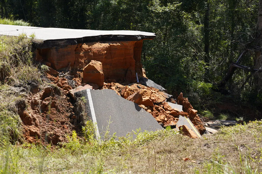 A section of Mississippi Highway 26 is damaged, Two people were killed and at least 10 others were injured when seven vehicles plunged into the deep hole on the dark rural two-lane highway, which collapsed after Hurricane Ida blew through Mississippi, in the Crossroads community, Miss., on Aug. 31, 2021. (AP Photo/Rogelio V. Solis)