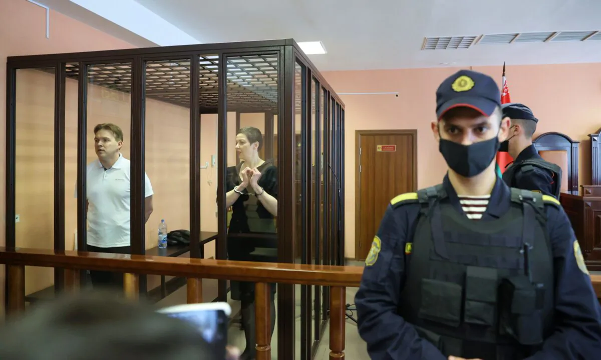 Belarusian opposition figures Maria Kolesnikova and Maxim Znak, charged with extremism and trying to seize power illegally, stand inside a defendants' cage as they attend a court hearing in Minsk, Belarus, on Sept. 6, 2021. (Ramil Nasibulin/BelTA/Handout via Reuters)