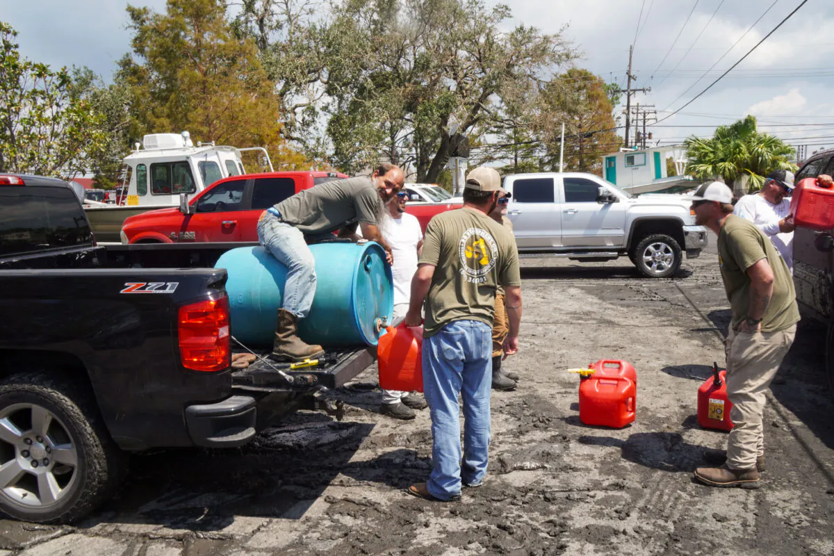 Bobby Matherne sits on a gas barrel as locals prepare to refuel a cell phone tower in Jefferson Parish, La., on Sept. 4, 2021. (Jackson Elliott/The Epoch Times)
