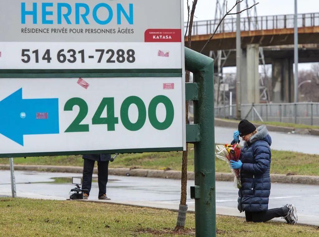 A woman prays in front of the Herron seniors residence on April 13, 2020 in Dorval near Montreal's Trudeau airport. (The Canadian Press/Ryan Remiorz)
