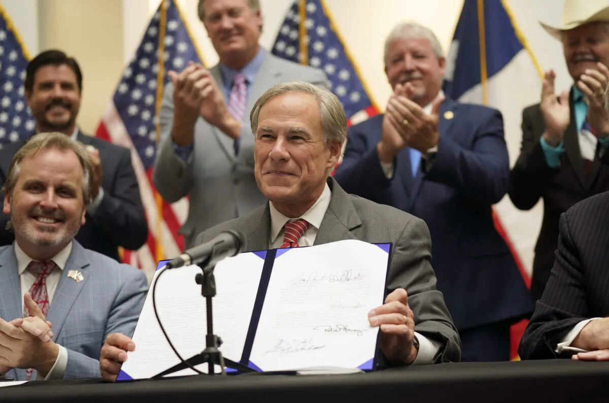 Texas Gov Greg Abbott shows off Senate Bill 1, also known as the election integrity bill, after he signed it into law in Tyler, Texas, on Sept. 7, 2021. (LM Otero/AP Photo)