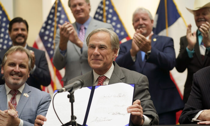 Texas Gov Greg Abbott shows off Senate Bill 1, also known as the election integrity bill, after he signed it into law in Tyler, Texas, on Sept. 7, 2021. (LM Otero/AP Photo)