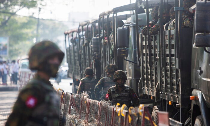 Soldiers stand next to military vehicles as people gather to protest against the military coup, in Yangon, Burma, on Feb. 15, 2021. (Stringer/Reuters)