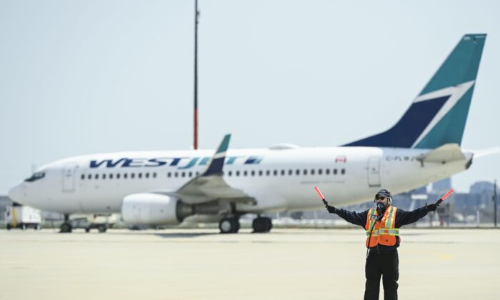 A ground controller works as a WestJet plane sits on the tarmac at Pearson International Airport in Toronto on April 27, 2021. (Nathan Denette/The Canadian Press)