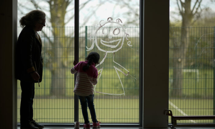 A young girl paints a picture of herself on the school window as children of key workers take part in school activities at Oldfield Brow Primary School in Altrincham, England, on April 8, 2020. (Christopher Furlong/Getty Images)
