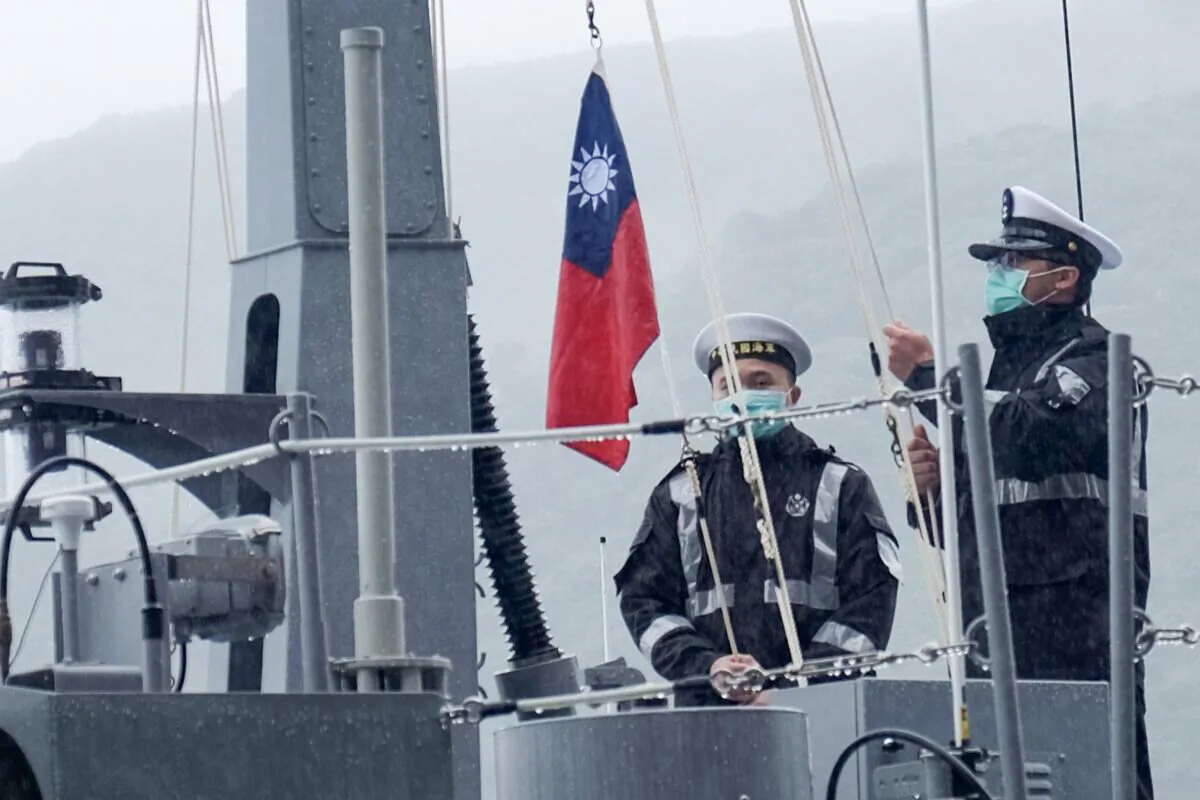 Two navy sailors raise Taiwan's national flag during an official ceremony at a shipyard in Su'ao, a township in eastern Taiwan's Yilan County, on Dec. 15, 2020. (Sam Yeh/AFP via Getty Images)