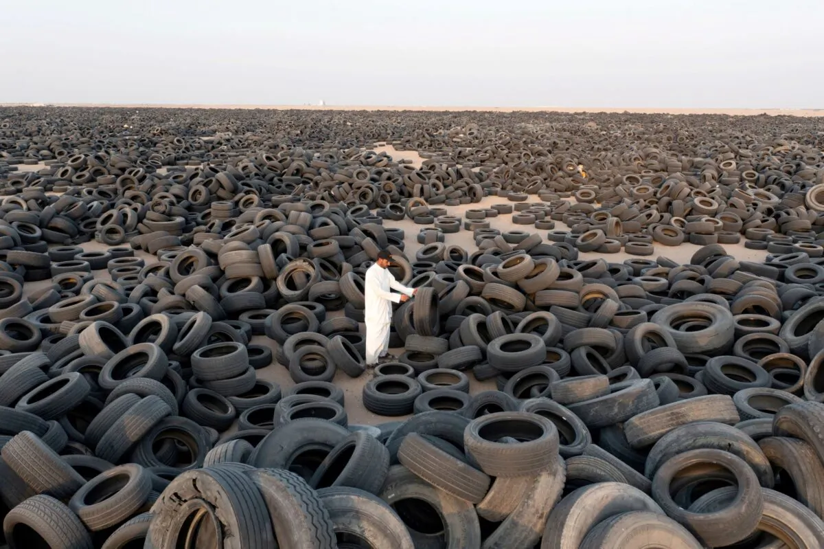 A Syrian contractor, Ibrahim Kamal, stands amongst used tires destined for recycling in Salmi, Kuwait, on Sep. 4, 2021. (Stephanie McGehee/Reuters)