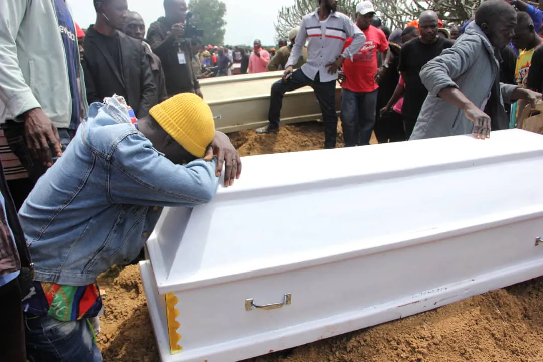 A boy weeps on a coffin at a mass funeral at Yelwan Zangam, Nigeria, on Aug. 28, 2021. (Masara Kim/The Epoch Times)