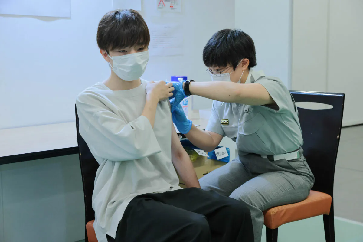 A Tokyo fire brigade staff member (R) administers a dose of the COVID-19 vaccine at Aoyama University in Tokyo on Aug. 2, 2021. (Stanislav Kogiku/POOL/AFP via Getty Images)