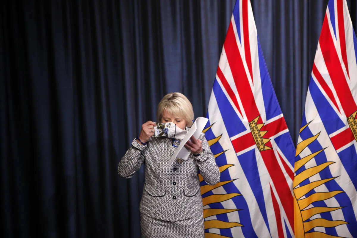 B.C. Provincial Health Officer Dr. Bonnie Henry puts on her mask following discussion of details about the COVID-19 vaccine card set to arrive in mid-September 2021, at a press conference at the provincial legislature in Victoria on Aug. 23, 2021. (The Canadian Press/Chad Hipolito)