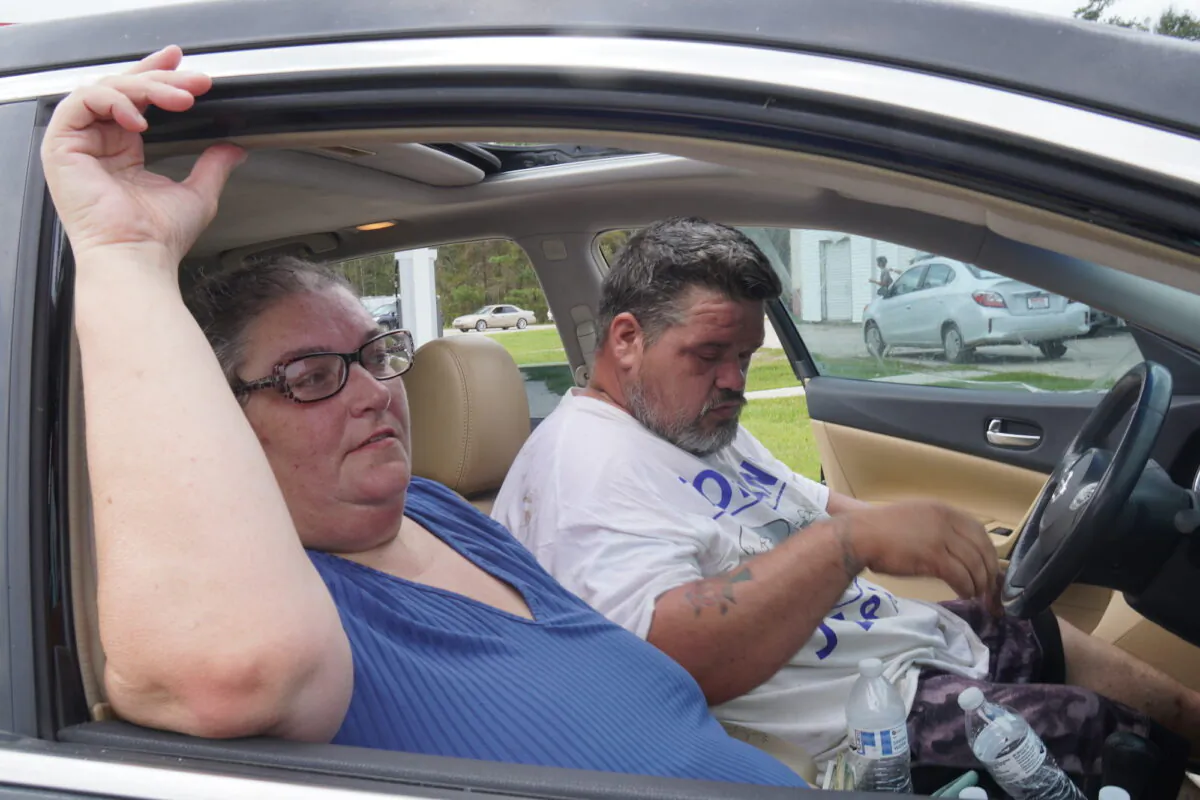 Clarence and Nyeki Bright endure the heat as they wait for gasoline at Big Boss Travel Plaza in Tickfaw, La., on Sept. 3, 2021. (Jackson Elliott/The Epoch Times)