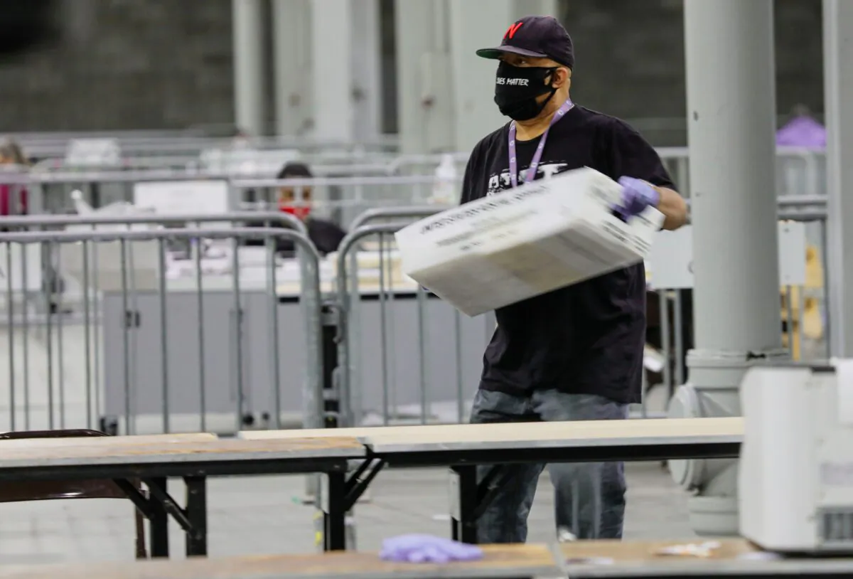 A worker carries a bin of ballots to be scanned at the Georgia World Congress Center in Atlanta, Georgia on Jan. 5, 2021. (Sandy Huffaker/AFP via Getty Images)