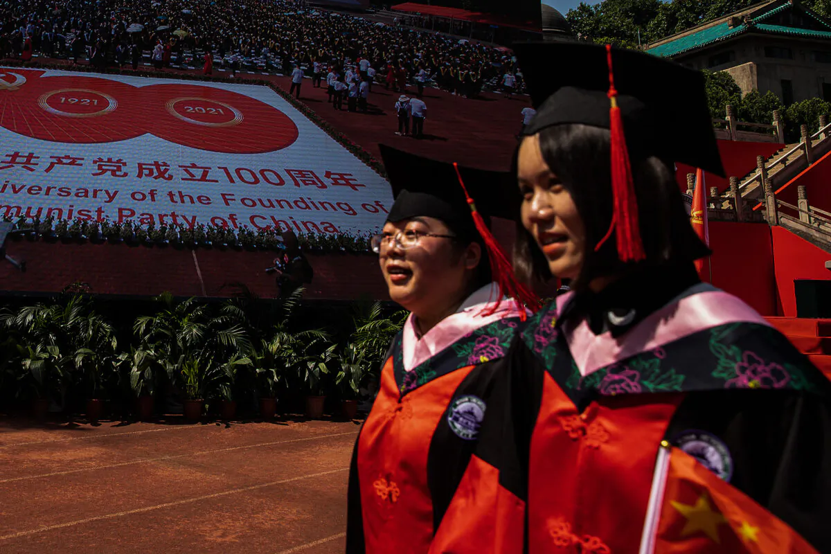 Two graduates pass by a big screen showing the centenary of the CCP at Wuhan University in Wuhan, China, on June 23, 2021. (Getty Images)