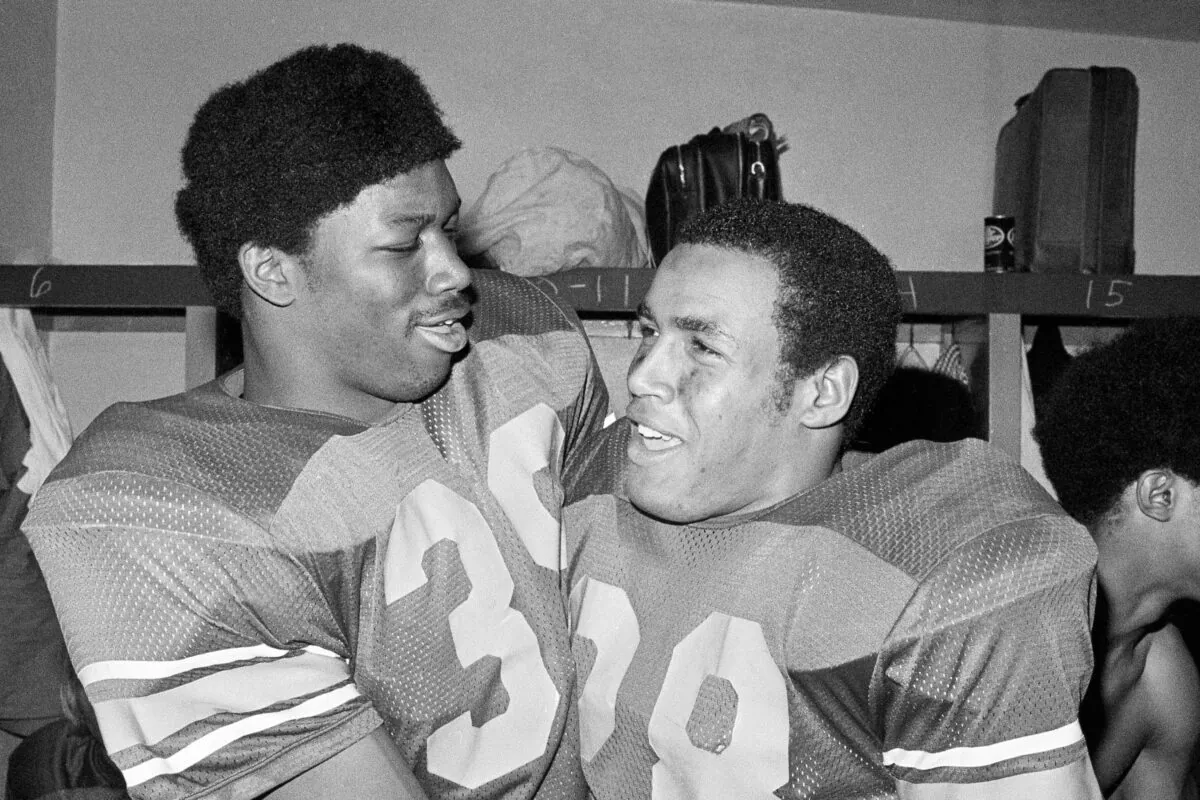 Southern California fullback Sam Cunningham (L) and running back Anthony Davis embraces in locker room after USC.s 42-17 triumph in the Rose Bowl NCAA college football game against Ohio State in Pasadena, Calif., on Jan. 1, 1973. (AP Photo)