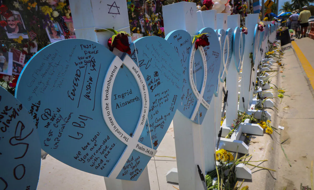 Wooden hearts with the names of victims are erected alongside the photos, flowers and other memorial items for victims of the Champlain Towers South collapse in Surfside, Fla., in a file photo. (Carl Juste/Miami Herald/TNS)