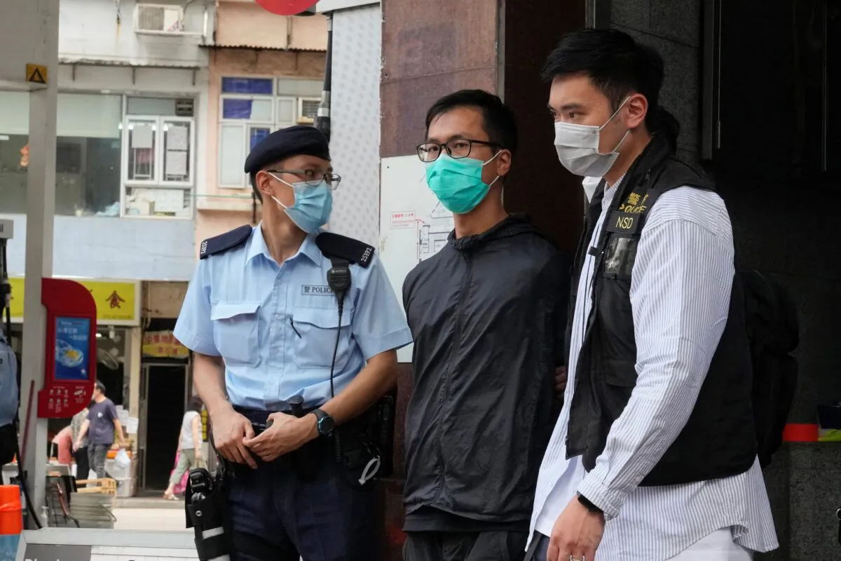 Simon Leung Kam-wai (C) a committee member of the Hong Kong Alliance in Support of Patriotic Democratic Movements of China, is escorted by police during an investigation of the June 4th Museum in Hong Kong. (Kin Cheung/AP photo)