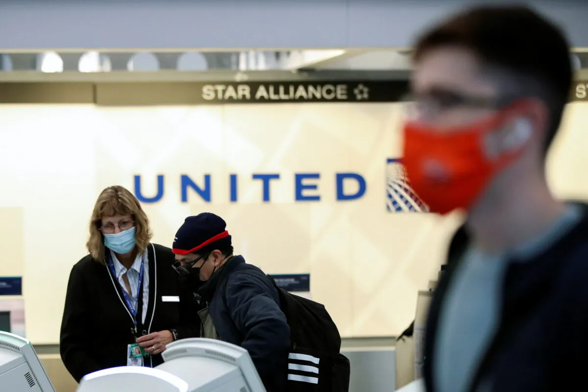 A United Airlines agent helps a customer check in for his flight at O'Hare International Airport in Chicago on Nov. 25, 2020. (Kamil Krzaczynski/Reuters)
