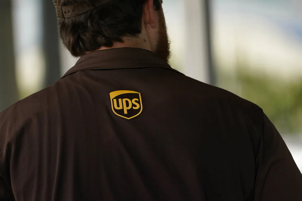 A UPS logo is on the shirt of a driver as he enters a United Parcel Service store with packages in Jackson, Miss., on July 26, 2021. (Rogelio V. Solis/AP Photo)
