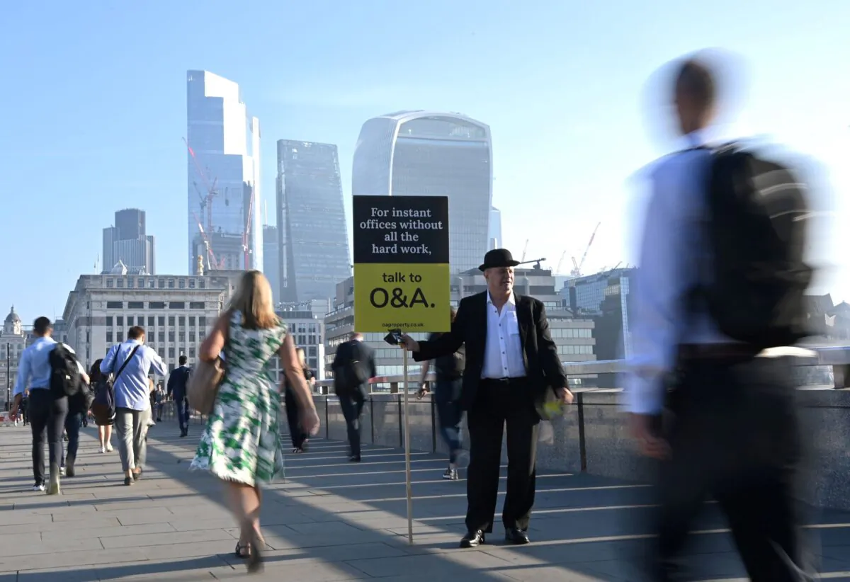 Workers pass by a sales person as they walk towards the City of London financial district as they cross London Bridge during the morning rush hour in London, Britain, on Sept. 8, 2021. (Toby Melville/Reuters)