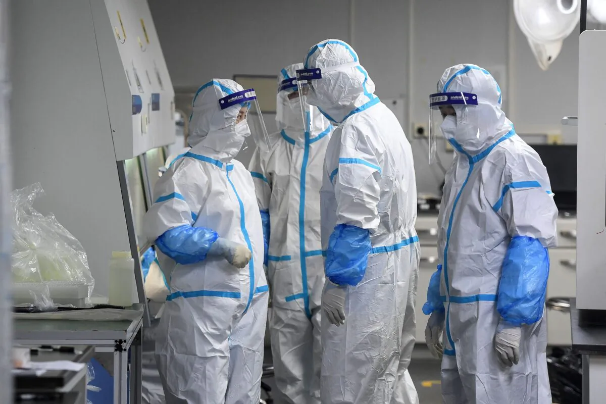 Laboratory technicians wearing personal protective equipment (PPE) work on samples to be tested for COVID-19 at the Fire Eye laboratory, a COVID-19 testing facility, in Wuhan in China's central Hubei Province, on Aug. 4, 2021. (STR/AFP via Getty Images)
