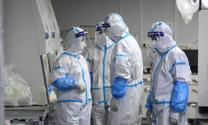 Laboratory technicians wearing personal protective equipment working on samples to be tested for COVID-19 at the Fire Eye laboratory, a COVID-19 testing facility, in Wuhan, Hubei Province, China, on Aug. 4, 2021. (STR/AFP via Getty Images)