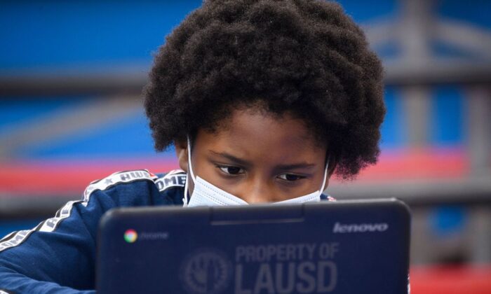 A child wears a face mask as they attend an online class at a learning hub inside the Crenshaw Family YMCA during the Covid-19 pandemic in Los Angeles, Calif., on Feb. 17, 2021. (Patrick T. Fallon/AFP via Getty Images)