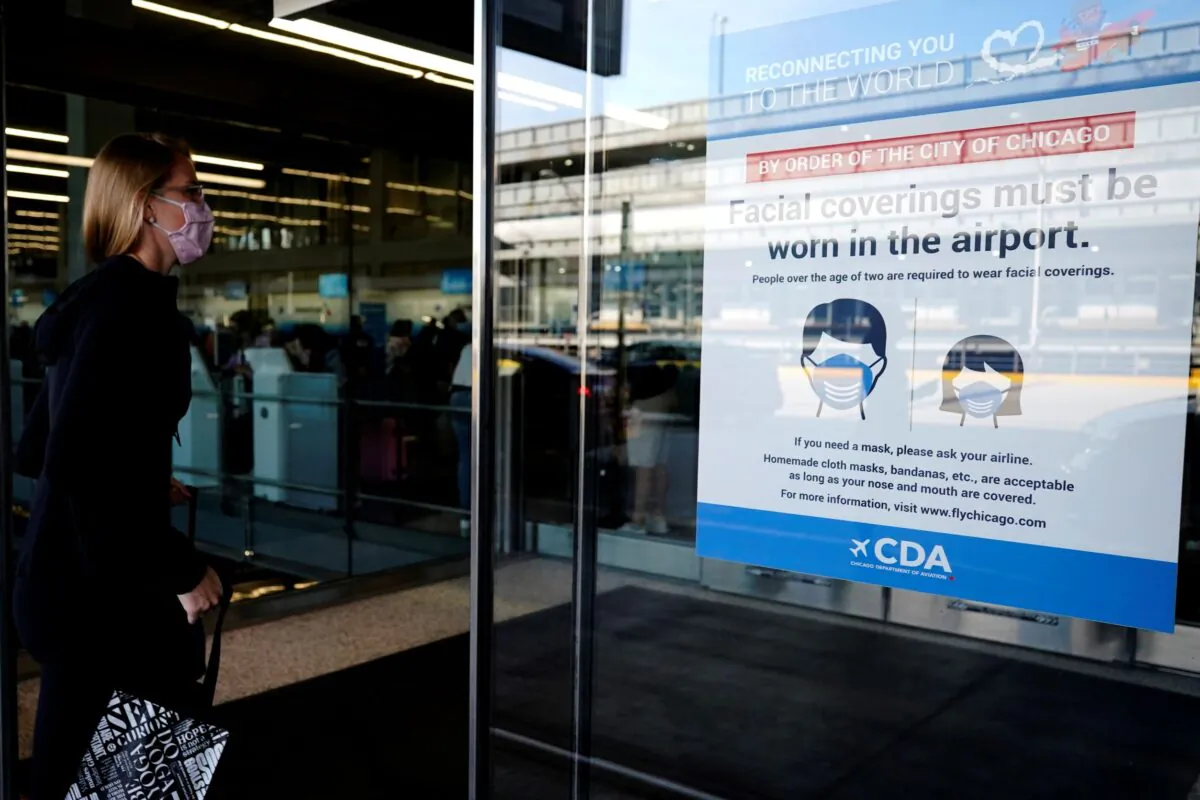 A traveler walks in Terminal 3 as a sign stating face coverings are required is displayed at O'Hare International Airport in Chicago on July 2, 2021. (Nam Y. Huh/AP Photo)

