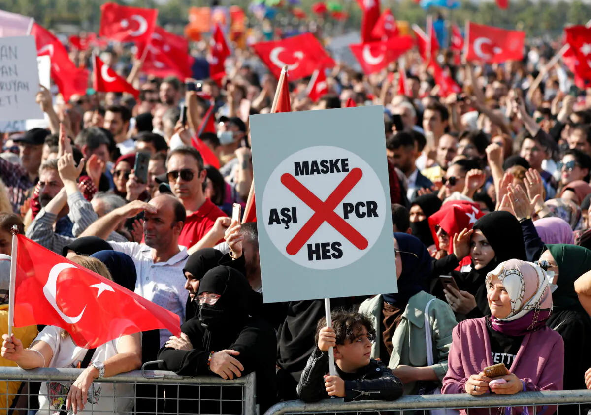 A boy holds a placard as demonstrators wave Turkish flags during a protest against official COVID-19-related mandates, including vaccinations, tests, and masks, in Istanbul, Turkey, on Sept. 11, 2021. (Murad Sezer/Reuters)