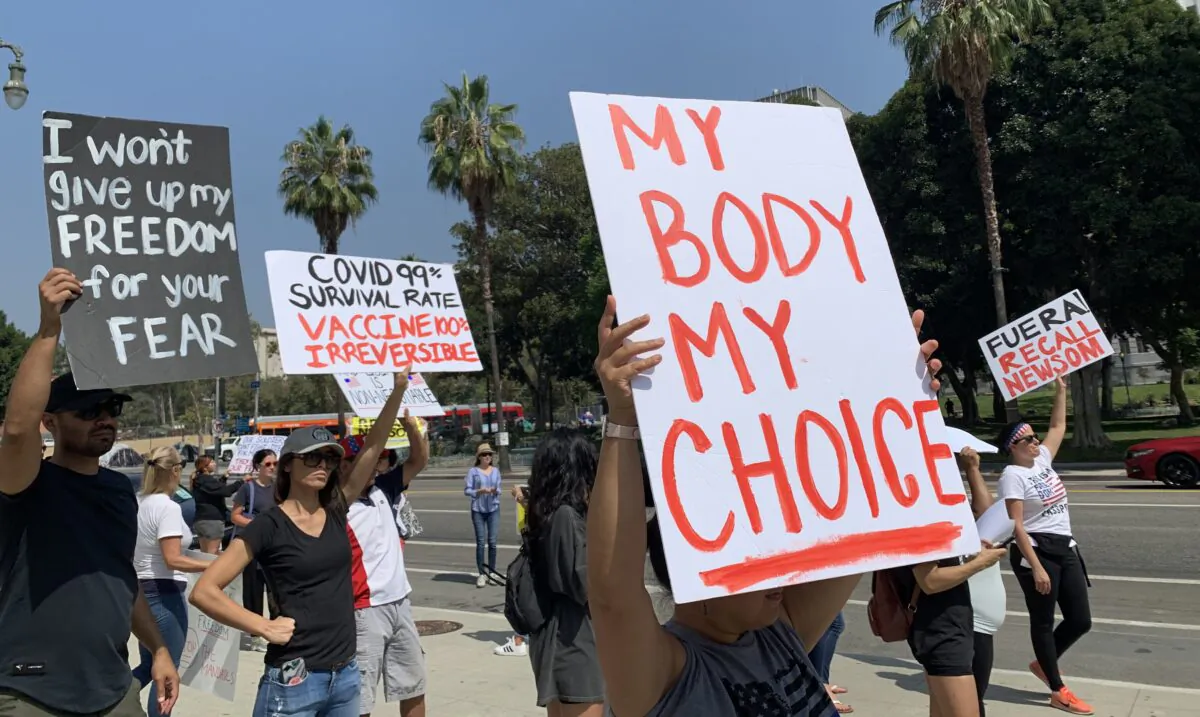 People hold signs in front of the Los Angeles Police Department (LAPD) headquarters to protest the government's policy of forcing frontline workers to be vaccinated against the CCP virus on Sept. 8, 2021. (Linda Jiang/The Epoch Times)