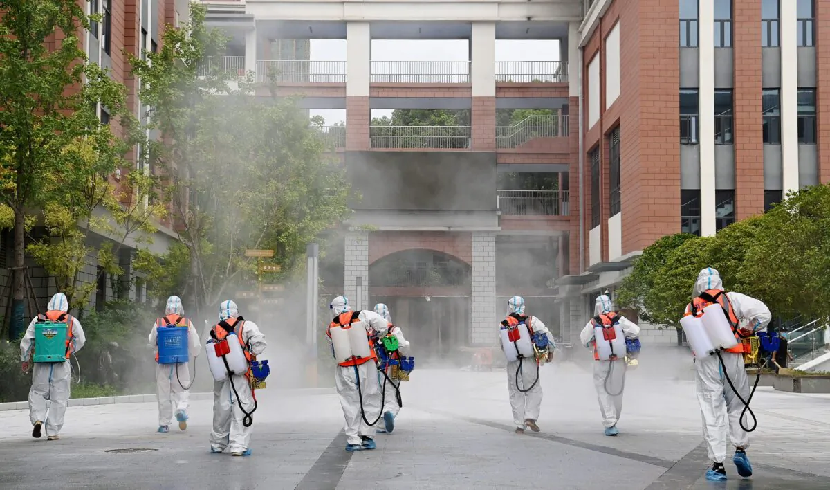 Workers in protective suits disinfect the compound of a primary school before schools reopen for the upcoming semester, in Wuhan, Hubei province, China, on Aug. 25, 2021. (China Daily via Reuters)