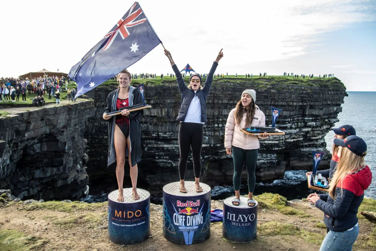 (L-R): Jessica Macaulay of Canada, Rhiannan Iffland, and Xantheia Pennisi of Australia celebrate on the podium during the final competition day of the fourth stop of the Red Bull Cliff Diving World Series at Downpatrick Head, Ireland, on Sept. 12, 2021. (Dean Treml/Red Bull Content Pool via Reuters)