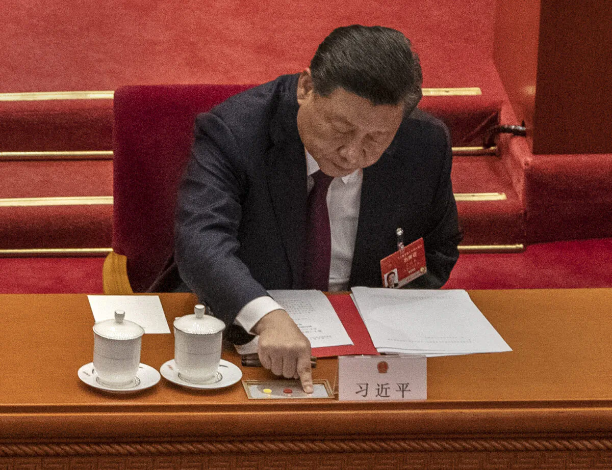 China's Leader Xi Jinping presses a button to vote in favor of a resolution to overhaul Hong Kong's electoral system at the Great Hall of the People in Beijing, on March 11, 2021. (Kevin Frayer/Getty Images)