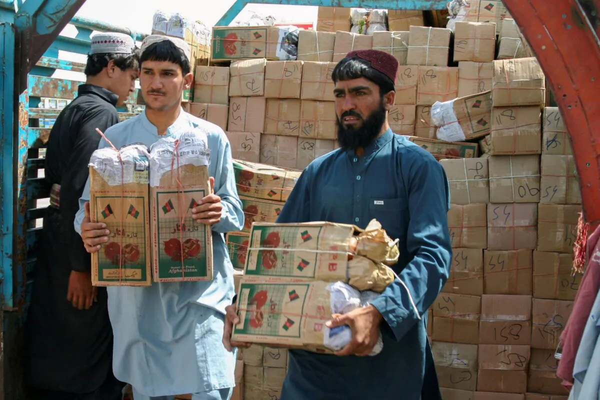People unload boxes of pomegranates from Afghanistan, from a truck at the 'Friendship Gate' crossing point, in the Pakistan-Afghanistan border town of Chaman, Pakistan, on Sept. 7, 2021. (Saeed Ali Achakzai/Reuters)