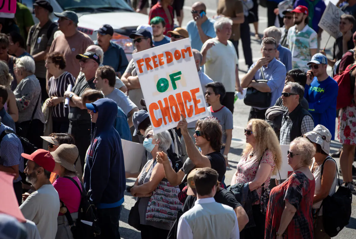 People listen to a speaker during a rally and march organized by those opposed to COVID-19 vaccination passports and public health measures, in Vancouver, on Sept. 8, 2021. (The Canadian Press/Darryl Dyck)