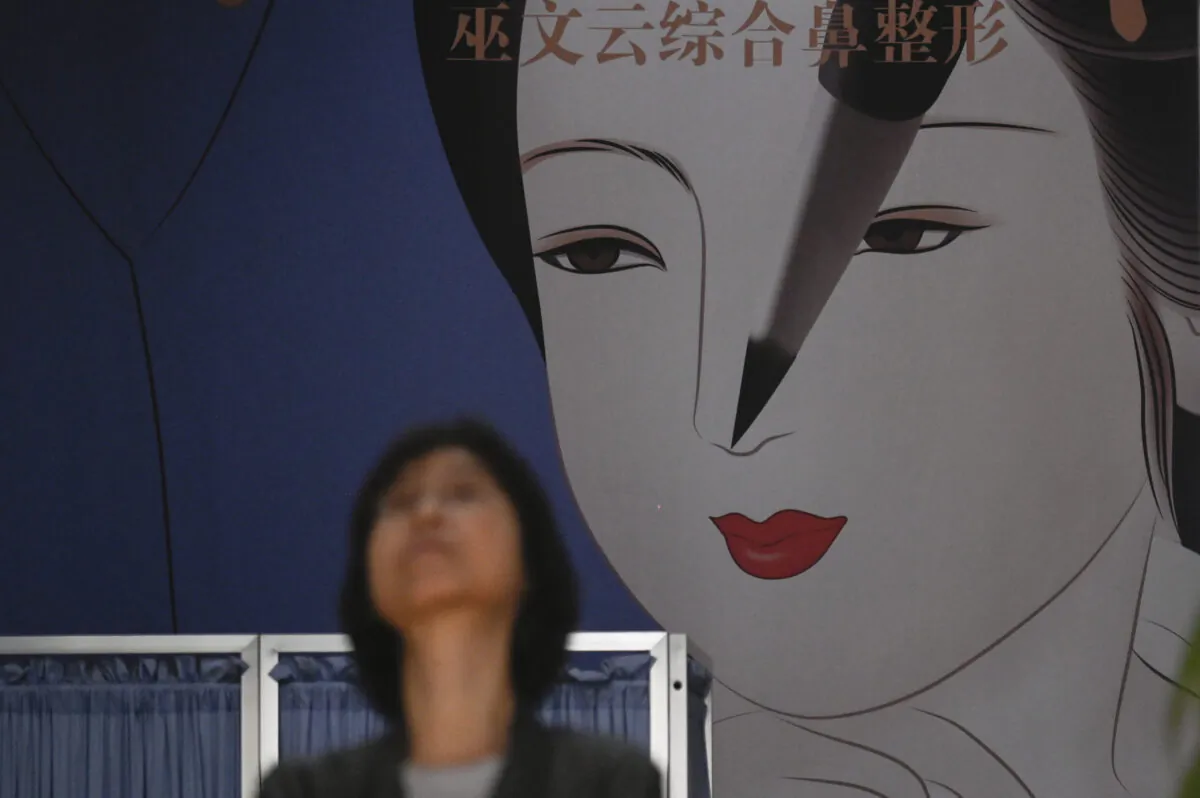 A woman walks past a large display at a plastic surgery clinic in Beijing on July 15, 2021. (Wang Zhao/AFP) 