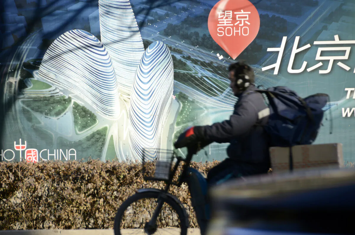 A Chinese man rides a tricycle past a billboard for the under-construction Wangjing SOHO complex by renowned architect Zaha Hadid in Beijing on Jan. 3, 2013. (Wang Zhao/AFP via Getty Images)