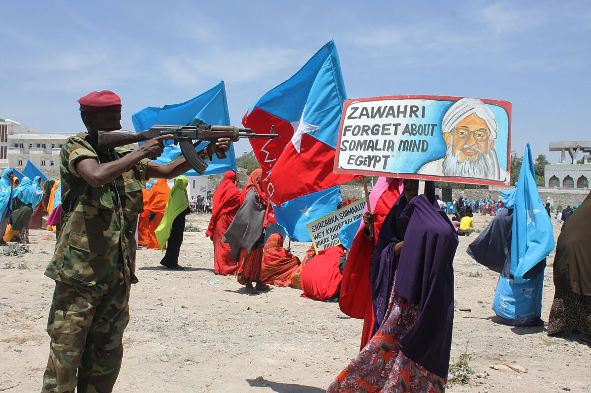 A Somali security soldier points his weapon at a poster bearing a photo of al-Qaeda leader Ayman al-Zawahiri during an anti Al-shabab rally in Mogadishu on Feb. 23, 2014. (Abdifitah Hashi Nor/AFP via Getty Images)