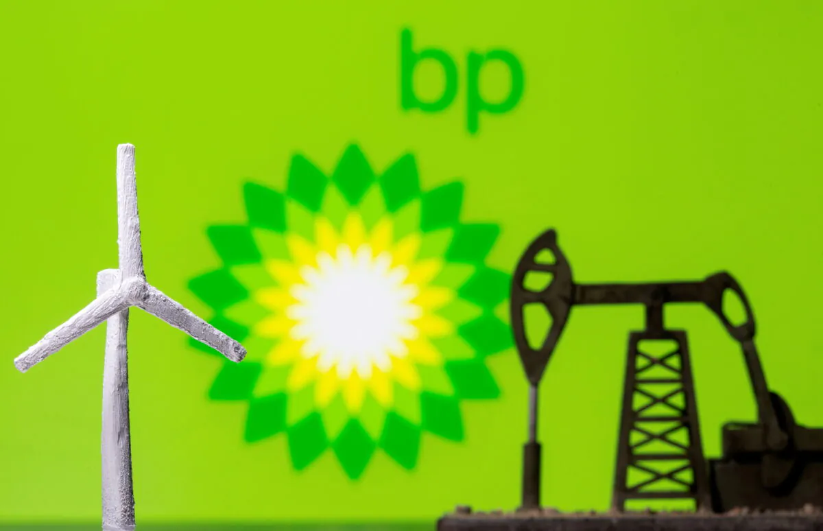 A 3D printed windmill and oil pump jack are seen in front of displayed BP logo, on Aug. 11, 2021. (Dado Ruvic/Reuters)