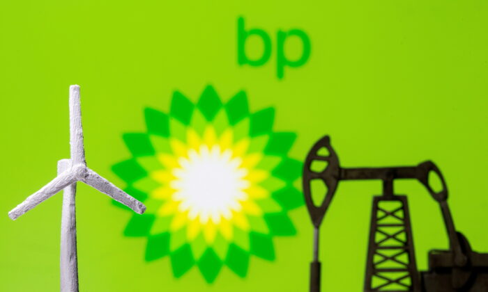 A 3D printed windmill and oil pump jack are seen in front of displayed BP logo, on Aug. 11, 2021. (Dado Ruvic/Reuters)