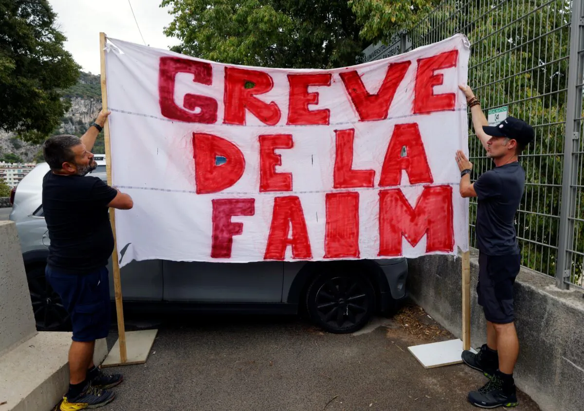 Thierry Paysant, security worker and firefighter at the Pasteur hospital, and Christophe, caregiver at the Pasteur hospital, hold a banner which reads "Hunger strike" to protest against France's restrictions, including compulsory health passes, to fight the COVID-19 pandemic, near the Abbaye Saint-Pons in Nice, France, on Sept. 15, 2021. (Eric Gaillard/Reuters)