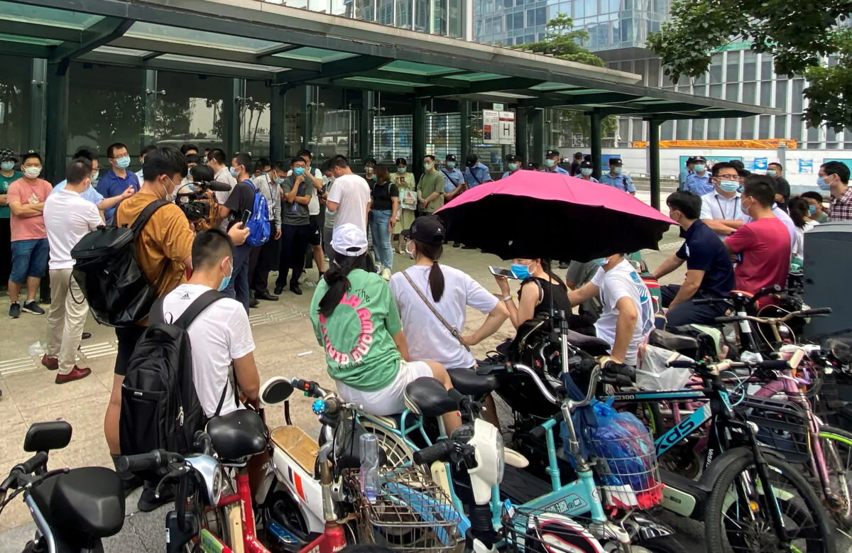 People gather to demand repayment of loans and financial products as security personnel guard outside Evergrande's headquarters in Shenzhen, Guangdong province, China, on Sept. 15, 2021. (David Kirton/Reuters)