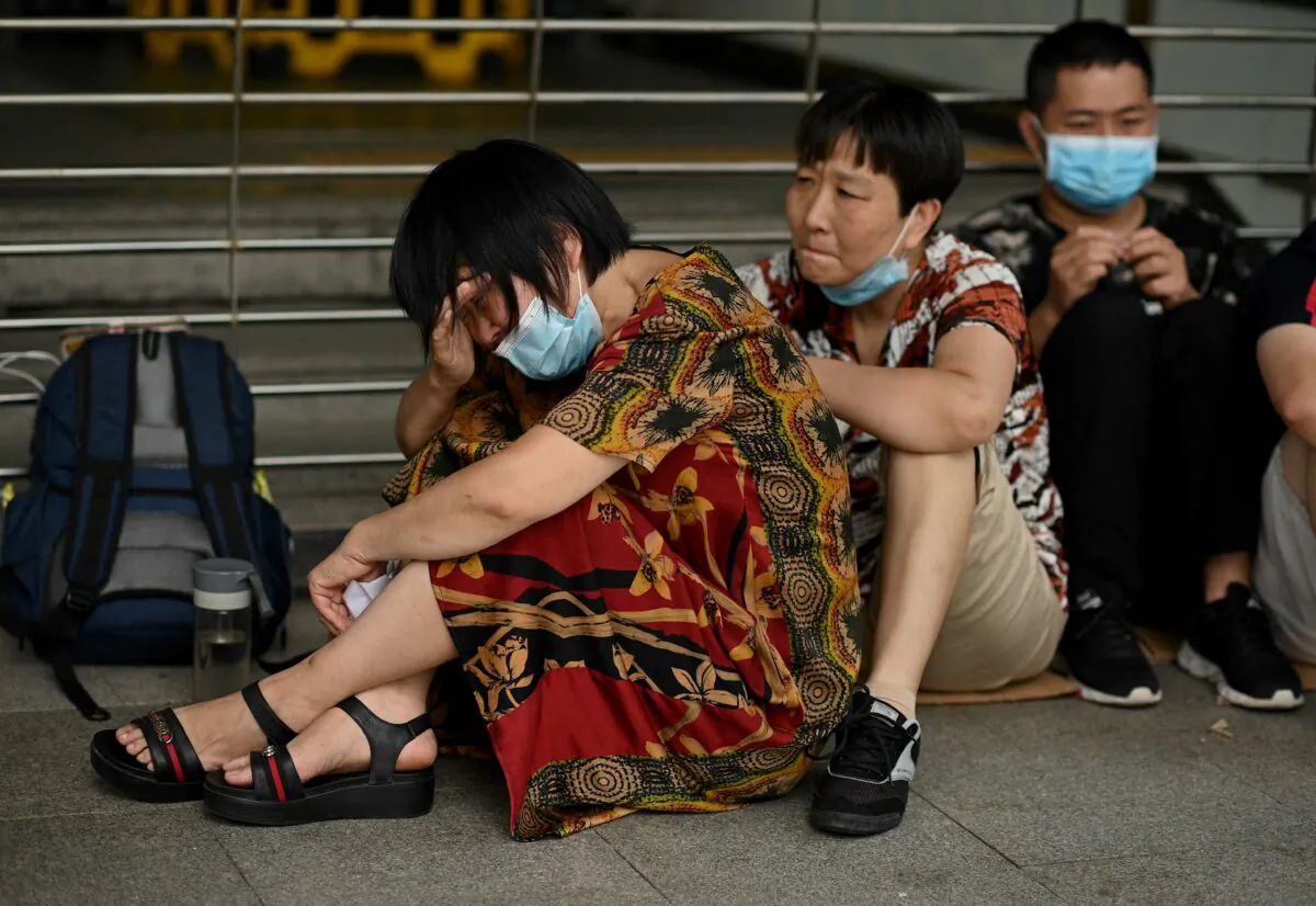A woman cries as she and other people gather at the Evergrande headquarters in Shenzhen, China on Sept. 16, 2021, as the Chinese property giant stated that it's facing "unprecedented difficulties," but denied rumors that it's about to go under. (Noel Celis/AFP via Getty Images)